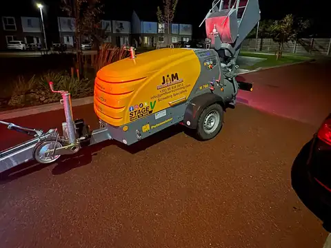 JAM Floor Screeding's yellow screed pump on its trailer at night